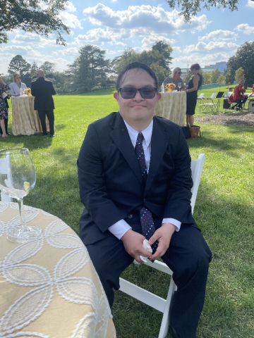 Gabe Martinez, in his formal suit, sitting on a chair on the White House lawn