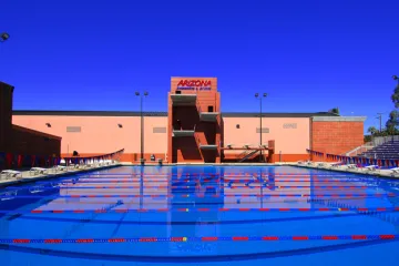 an outdoor swimming pool in front of a building with UArizona branding