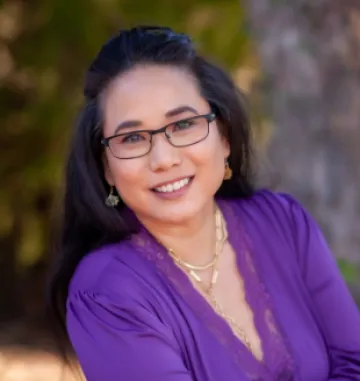 Headshot of Lorie Sandaine, a woman with long black hair wearing glasses and a purple blouse.