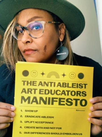 Jennifer White Johnson holds up a copy of The Anti Ableist Art Educator's Manifesto