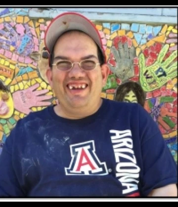 Joey wearing a U of A t-shirt and red hat and is smiling at the camera
