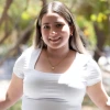Ana Fernandez, a woman with light skin and blonde hair, wearing a white top, standing outside near some trees