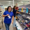 Two student workers stocking store shelves and smiling