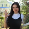 Alehxia Apodaca, a young person with long dark hair, wearing a black top over a white shirt, in front of a glass building
